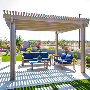 Pergola covering a patio area with a table and blue chairs