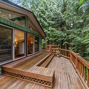Home with wooden deck leading out from a sliding door on the side of the home