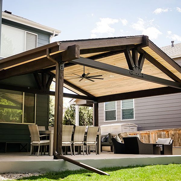 Completed project by Solomon Brothers Construction Services - House backyard patio with chairs under a large and brown patio cover